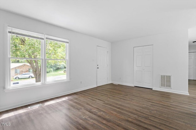 spare room featuring dark wood-style floors and baseboards