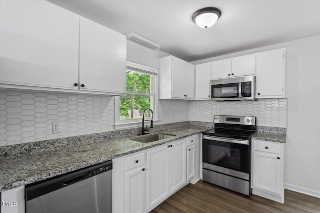 kitchen with appliances with stainless steel finishes, a sink, white cabinets, and stone countertops