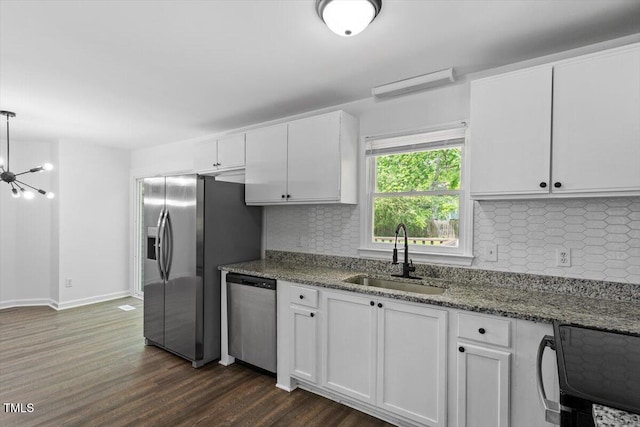 kitchen with appliances with stainless steel finishes, a sink, white cabinetry, and tasteful backsplash