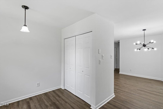 interior space with dark wood-style floors, a chandelier, and baseboards