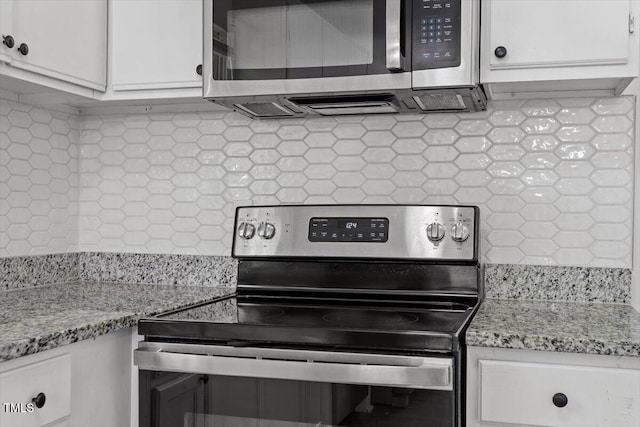 kitchen featuring stainless steel appliances, decorative backsplash, white cabinets, and light stone counters