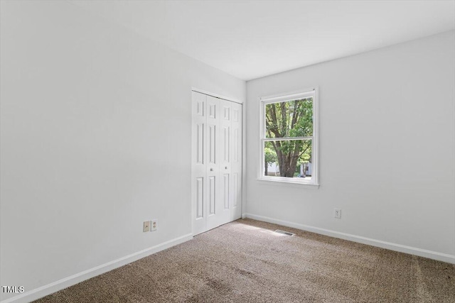 carpeted empty room featuring baseboards