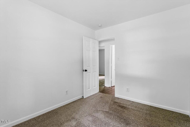 carpeted spare room featuring baseboards