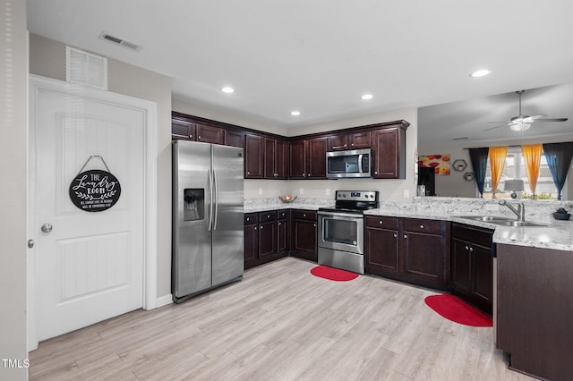 kitchen with stainless steel appliances, a sink, a peninsula, light wood-type flooring, and recessed lighting