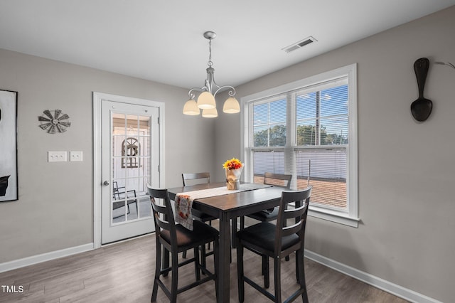 dining space with a chandelier, wood finished floors, and baseboards
