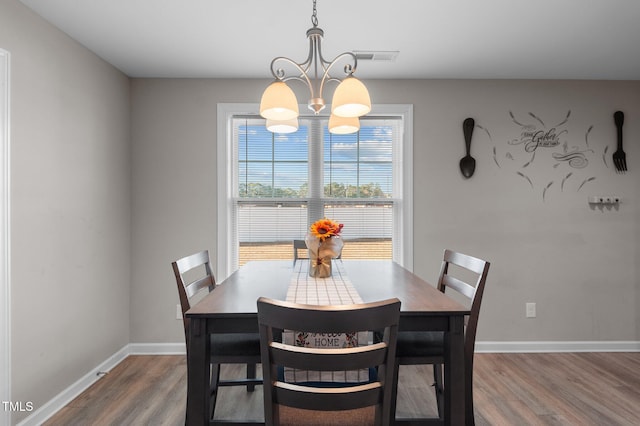 dining room with a chandelier, wood finished floors, and baseboards
