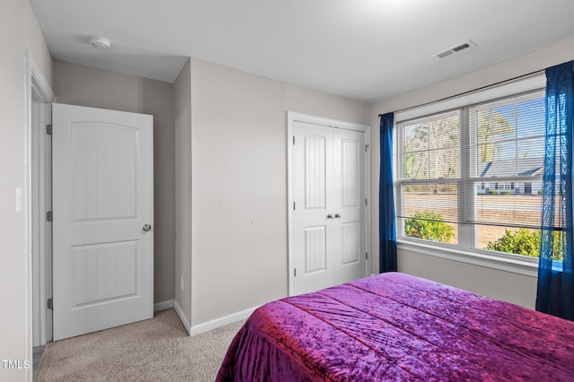 bedroom with light carpet, baseboards, and a closet