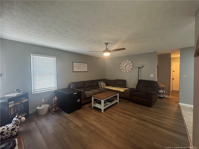living room featuring wood finished floors, a textured ceiling, ceiling fan, and baseboards