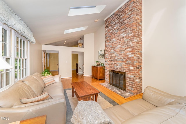 living room featuring a skylight, wood finished floors, a fireplace, baseboards, and high vaulted ceiling