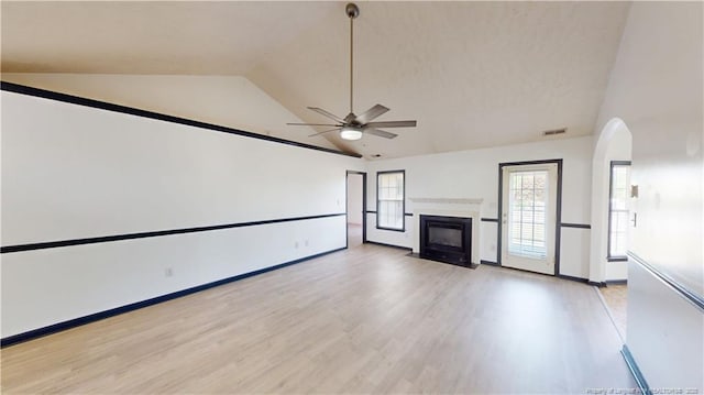 2500 Forest Lodge Dr, Fayetteville, NC 28306 - unfurnished living room featuring ceiling fan, light wood-style floors, a fireplace with flush hearth, high vaulted ceiling, and arched walkways
