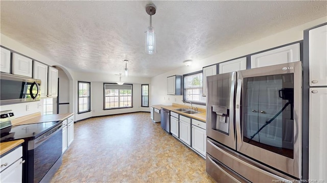 2500 Forest Lodge Dr, Fayetteville, NC 28306 - kitchen featuring appliances with stainless steel finishes, a sink, a textured ceiling, decorative light fixtures, and arched walkways
