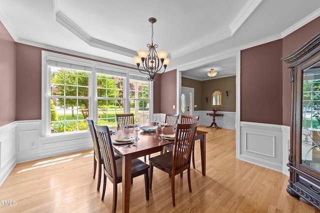 dining space featuring plenty of natural light, a chandelier, a wainscoted wall, light wood finished floors, and a tray ceiling