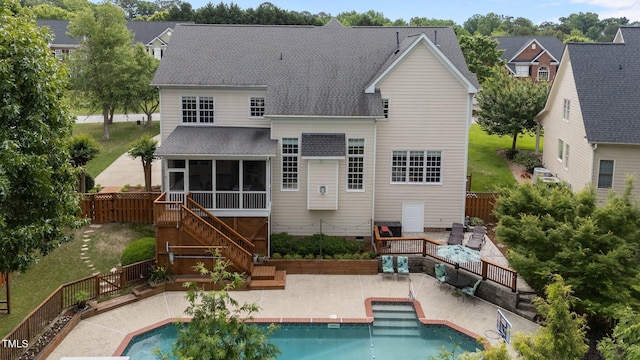 rear view of house with a sunroom, a shingled roof, a patio area, stairs, and a fenced backyard