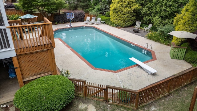 view of pool with a patio area, fence, a diving board, and a wooden deck