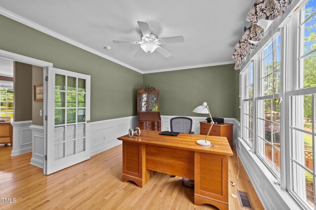 office area with light wood-style flooring, ornamental molding, ceiling fan, and a wainscoted wall