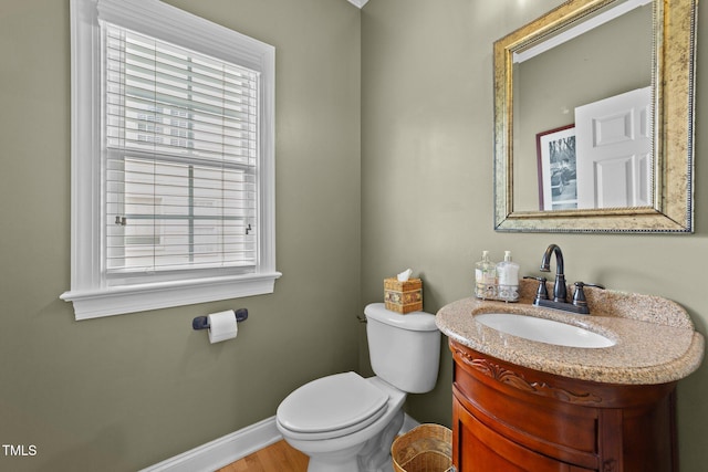 half bathroom featuring baseboards, toilet, vanity, and wood finished floors