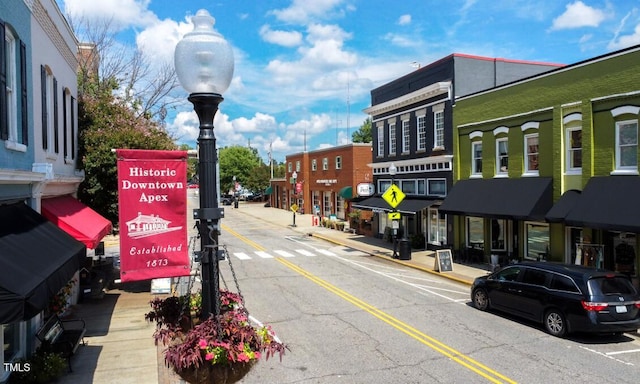view of asphalt road with sidewalks, street lighting, and curbs