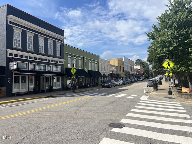 view of asphalt road with sidewalks, traffic signs, and curbs