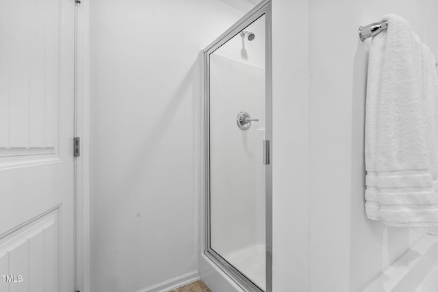 bathroom featuring a shower stall and baseboards