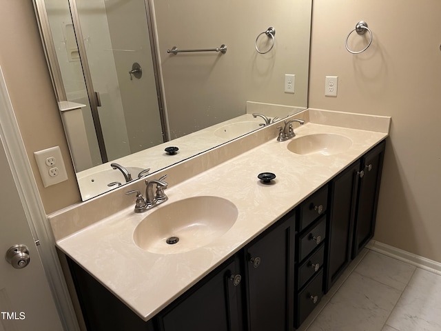 bathroom featuring marble finish floors, double vanity, and baseboards