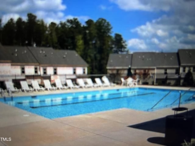 community pool with a patio and fence