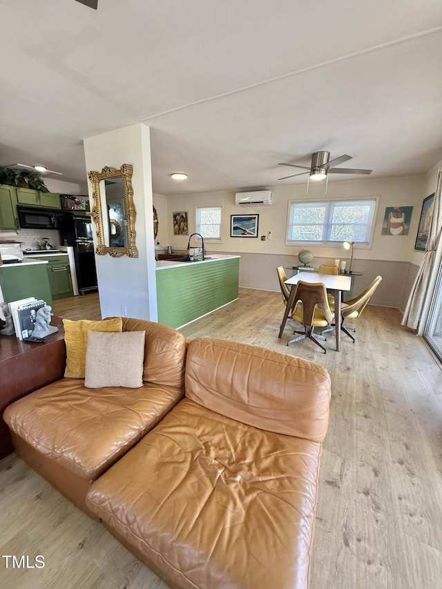 living room featuring a wall mounted air conditioner, light wood-style flooring, and healthy amount of natural light