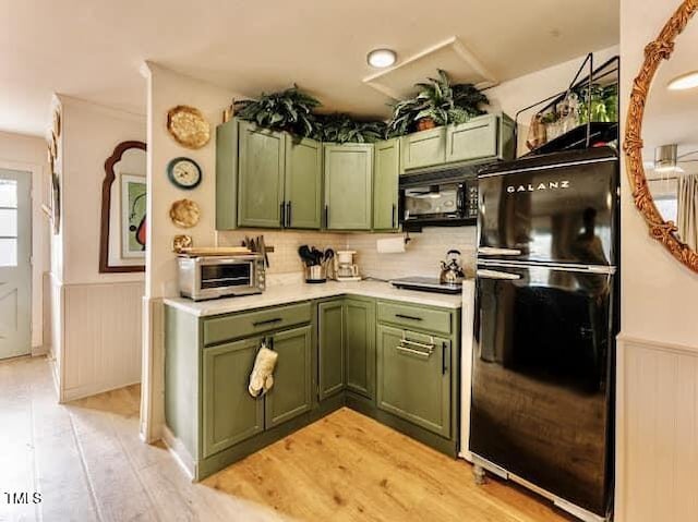 kitchen featuring green cabinets, light countertops, wainscoting, wall oven, and light wood-style flooring