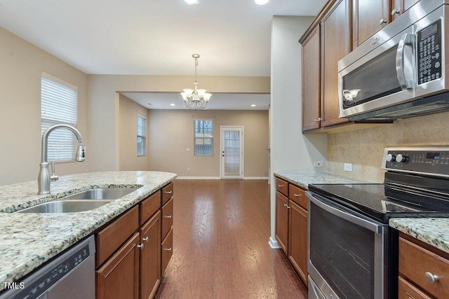 kitchen with appliances with stainless steel finishes, a sink, a chandelier, decorative backsplash, and dark wood-style floors