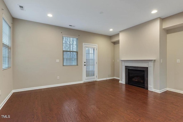 unfurnished living room featuring wood finished floors, healthy amount of natural light, recessed lighting, baseboards, and a fireplace