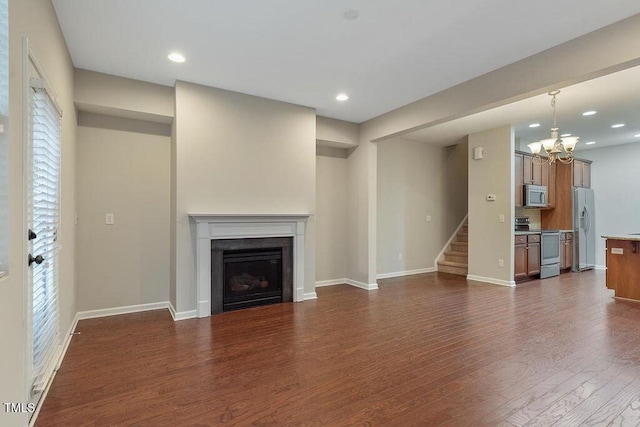 unfurnished living room featuring dark wood-style floors, stairs, baseboards, a chandelier, and a fireplace