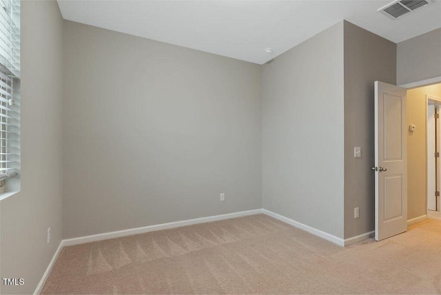 empty room featuring light colored carpet and baseboards