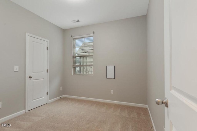 spare room with light carpet and baseboards