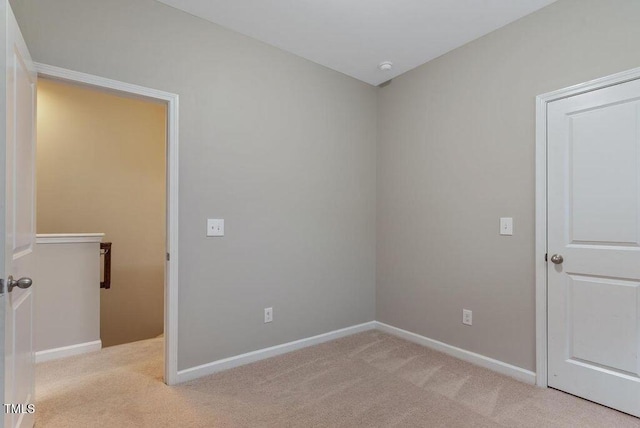 unfurnished room with light carpet and baseboards