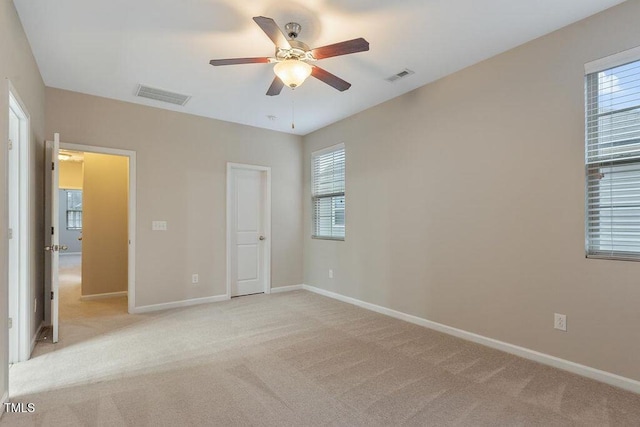unfurnished bedroom with baseboards, light carpet, and multiple windows