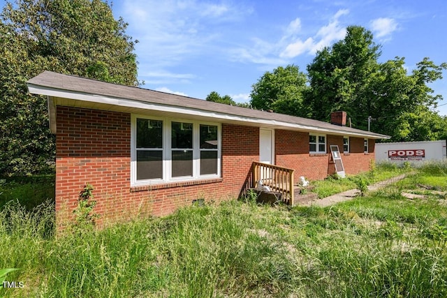 ranch-style house featuring brick siding and a chimney