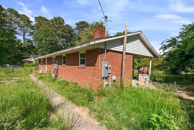 view of side of property featuring brick siding and a chimney