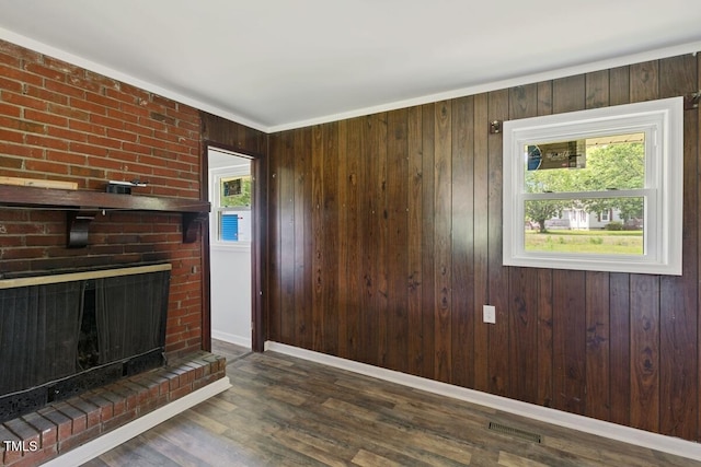unfurnished living room featuring wood finished floors, a fireplace, wooden walls, and baseboards