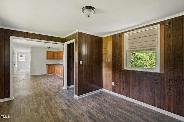 empty room with wooden walls, baseboards, dark wood-style floors, and ornamental molding