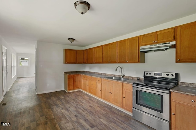 kitchen with under cabinet range hood, stainless steel electric range, a sink, dark wood finished floors, and baseboards