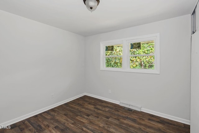 spare room with baseboards and dark wood-style floors