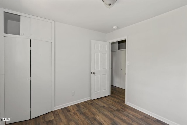 unfurnished bedroom with baseboards, dark wood-style floors, and a closet