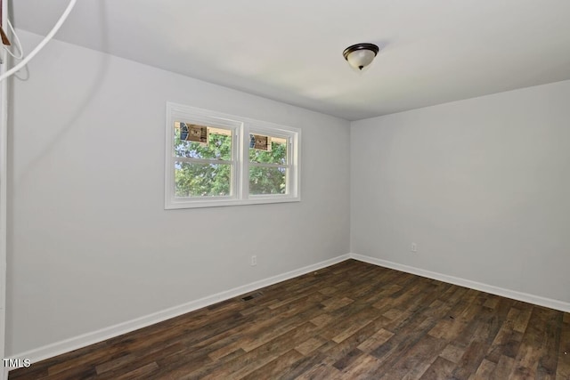 spare room featuring dark wood finished floors and baseboards