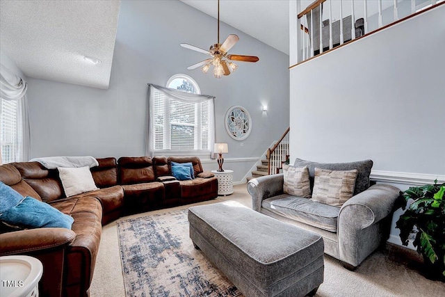 living room with carpet flooring, ceiling fan, high vaulted ceiling, and stairway