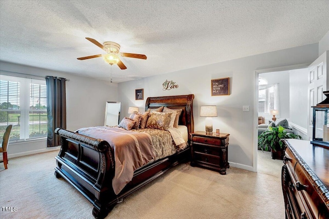 bedroom featuring light colored carpet, baseboards, a textured ceiling, and a ceiling fan