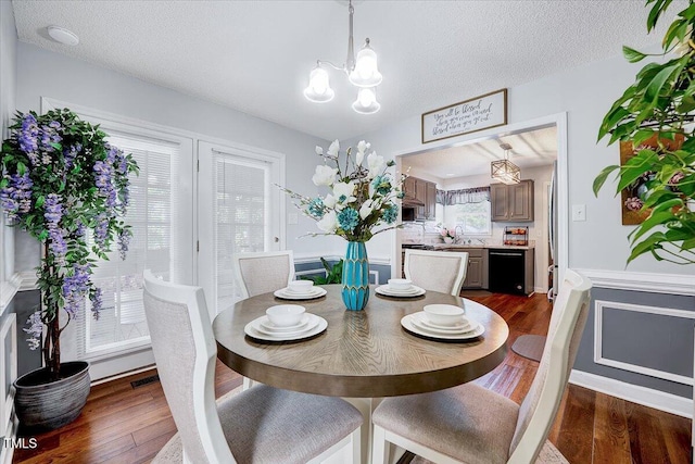 dining area with a chandelier, dark wood-type flooring, and a textured ceiling