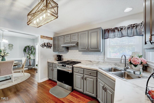 kitchen with gray cabinetry, stainless steel gas range oven, under cabinet range hood, and a textured ceiling