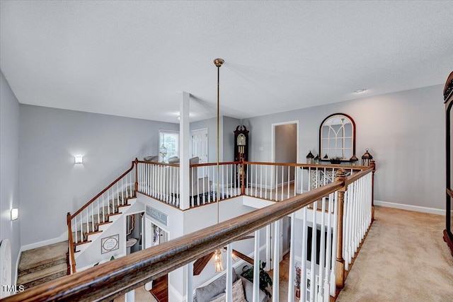 hall with carpet, baseboards, and an upstairs landing