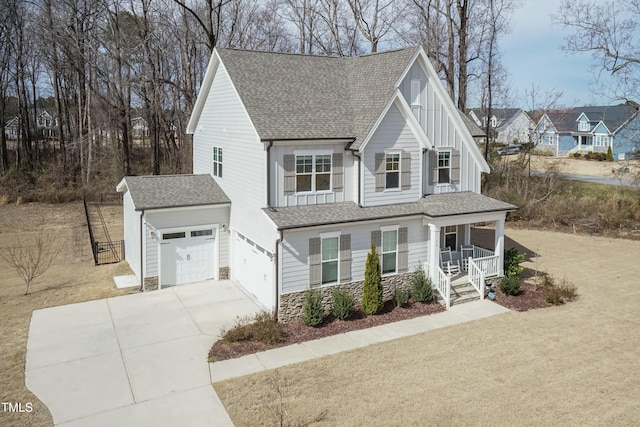 76 Freewill Pl, Raleigh, NC 27603 - view of front facade featuring covered porch, stone siding, a shingled roof, driveway, and board and batten siding
