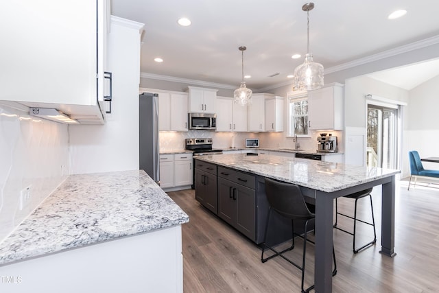 76 Freewill Pl, Raleigh, NC 27603 - kitchen featuring appliances with stainless steel finishes, a sink, white cabinets, a kitchen breakfast bar, and wood finished floors
