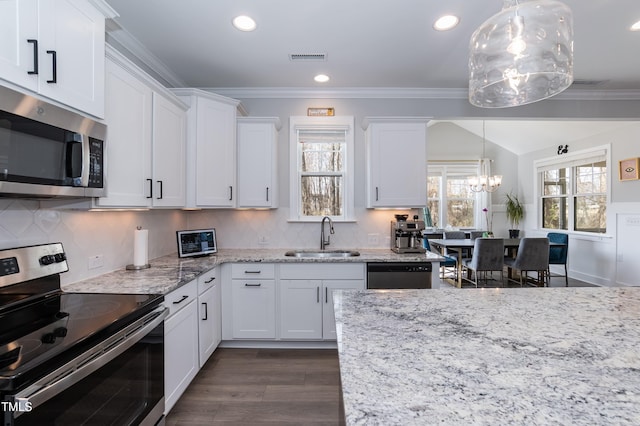 76 Freewill Pl, Raleigh, NC 27603 - kitchen featuring appliances with stainless steel finishes, a sink, a chandelier, white cabinets, and ornamental molding